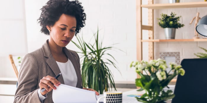 Business person looks at papers near plants